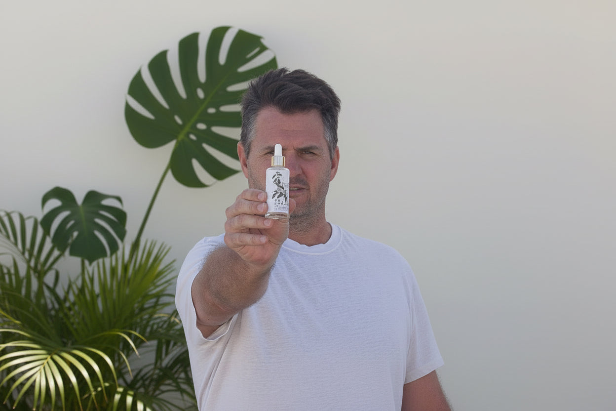 Man holding a bottle of Be You Skincare oil against a white background